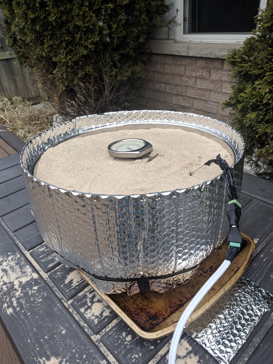 The same aluminum pot, now topped off with sand of the kettle heaters are not visible, and with an insulation layer on the outside.